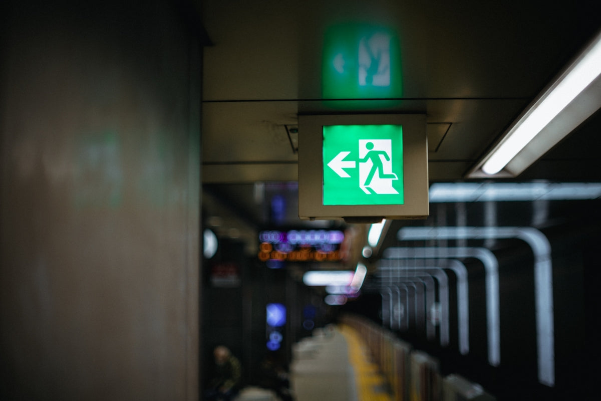 Green emergency exit sign with arrow pointing left.