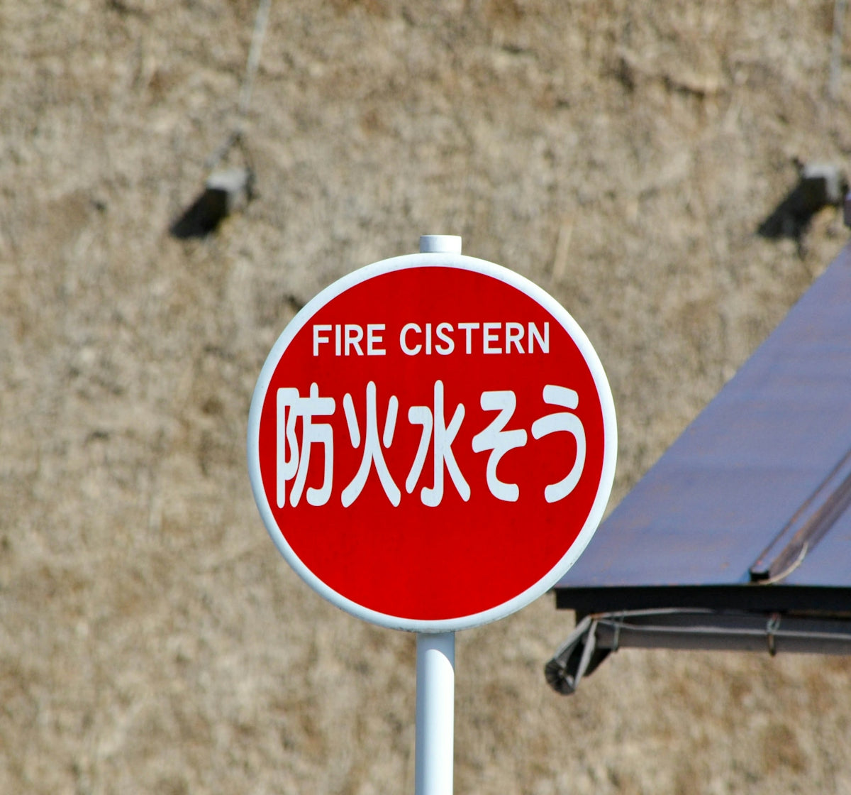 Red and white fire cistern sign with japanese text.
