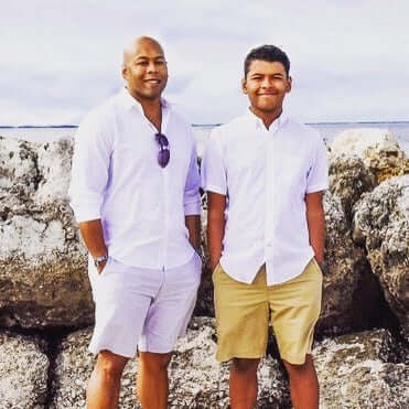 Two men standing on a rocky shoreline with ocean in the background